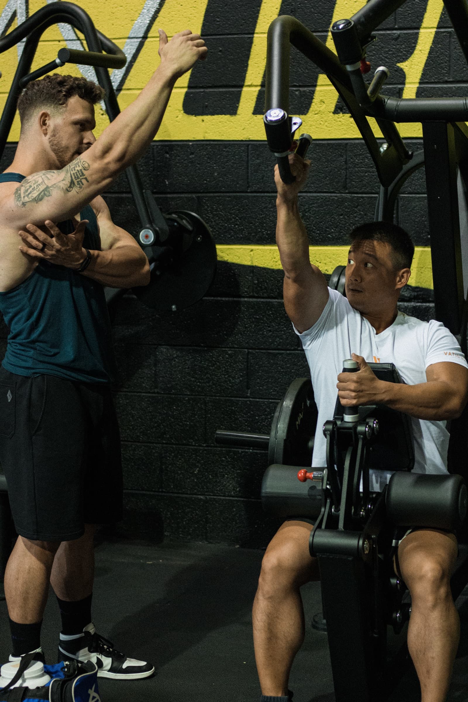 Phil demonstrating form while a client trains on a machine
